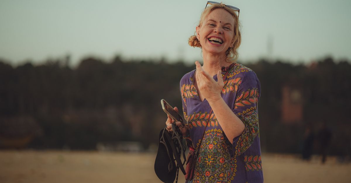 Joyful woman in a vibrant dress enjoying a beautiful day on the beach.