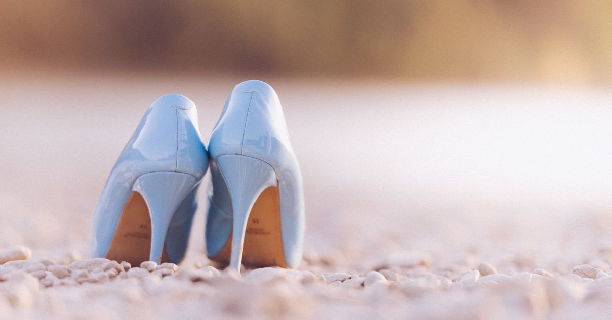 Stylish blue high heel shoes photographed on a tranquil pebble beach setting.