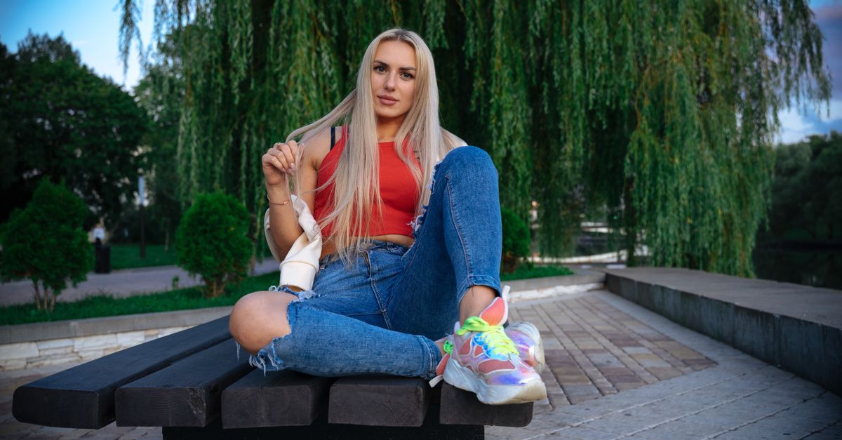 Young woman in casual attire relaxing on a bench in a Minsk park, Belarus.