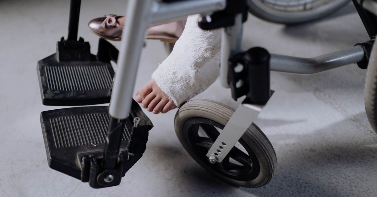 Close-up of an injured foot in a cast resting on a wheelchair, indoors.