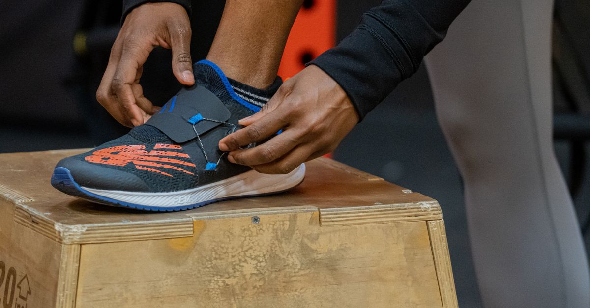 Close-up of a person fastening a sports shoe during a workout session, showcasing determination and athleticism.