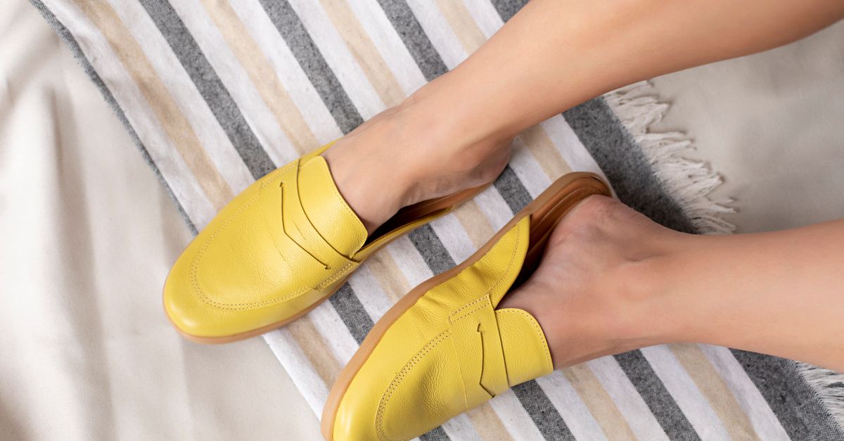 Top view of yellow loafers on a striped fabric background, showcasing fashion footwear.