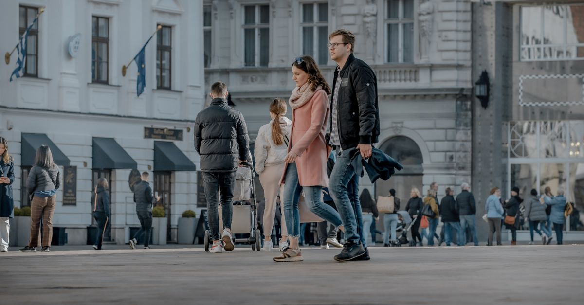 Couple walking in a busy European town square, showcasing city life and fashion.