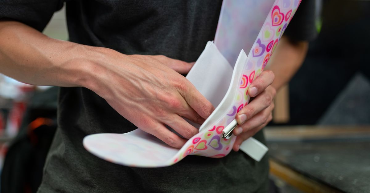 A person designing a vibrant, heart-patterned orthotic brace indoors, showcasing craftsmanship.