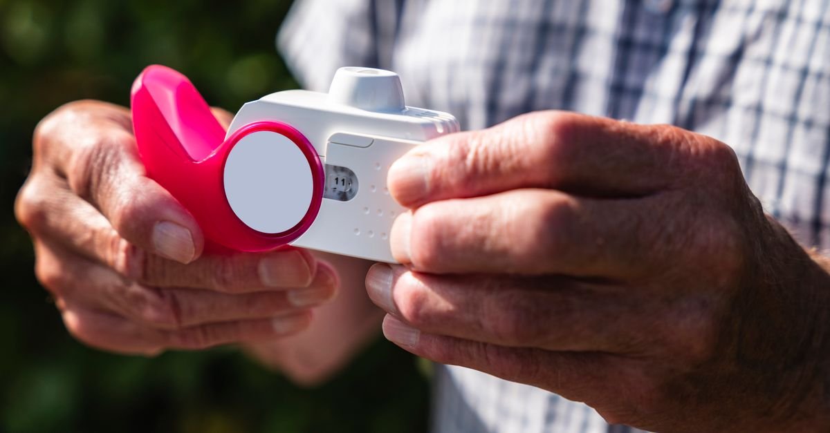 Close-up of senior hands holding an inhaler outdoors, showcasing health and respiratory care.